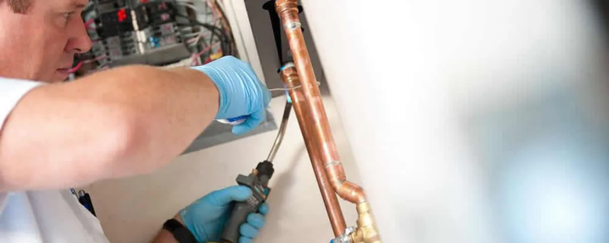 Water heater repair technician testing copper pipe connections and controls in Charlotte, NC